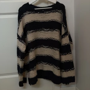 Randig stickad tröja från Urban Outfitters - Säljer en randig stickad tröja från Urban Outfitters i svart och beige. Tröjan har en avslappnad passform med långa ärmar och ett grovt stickat mönster. Perfekt för en mysig dag hemma eller en avslappnad dag ute.