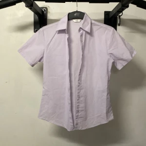 Ljuslila skjorta från Russell Collection - Säljer en stilren ljuslila skjorta från Russell Collection. Skjortan har korta ärmar och knappar framtill. Perfekt för en avslappnad men ändå uppklädd look. 💜