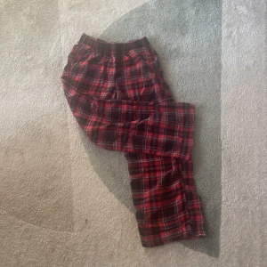 Röd- och svartrutiga byxor från H&M - Säljer ett par bekväma röd- och svartrutiga byxor från H&M. Perfekta för en avslappnad dag hemma. Byxorna har en elastisk midja för extra komfort.