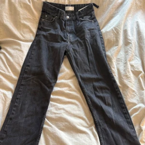 Svarta jeans från Bershka - Snygga svarta jeans från Bershka i en rak modell. De är högmidjade och har klassiska femficksdetaljer med knappar och dragkedja. Perfekta för en stilren look.