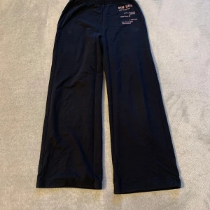 Svarta mjukisbyxor med tryck - Bekväma svarta mjukisbyxor med elastisk midja och tryck på ena benet. Perfekta för en avslappnad dag hemma eller lätt träning.