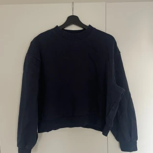 Marinblå sweatshirt från Weekday - Säljer en stilren svart sweatshirt från Weekday i storlek XS. Tröjan har en klassisk rund hals och långa ärmar med ribbade muddar. Perfekt för en avslappnad look.