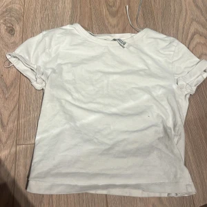 Vit t-shirt från Monki - Säljer en klassisk vit t-shirt från Monki. Den har en rund halsringning och korta ärmar. Perfekt basplagg för alla tillfällen. Skön och enkel att matcha med andra kläder.
