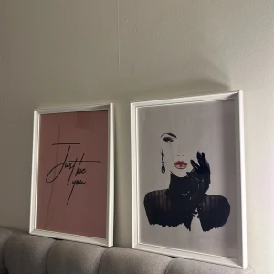 Väggkonst med text och illustration - Två stilrena tavlor i vita ramar. Den ena har en rosa bakgrund med texten 'Just be you' i svart. Den andra visar en elegant illustration av en kvinna med röda läppar och svarta handskar, samt ett örhänge.  För båda tavlorna 150kr