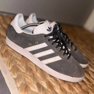 Adidas Gazelle skor  - Ett par gråa Adidas Gazelle i storlek 42. Passar perfekt nu till våren och sommaren med sin låga passform och luftiga creas. Enkel snörning, sitter perfekt på fötterna och skön dämpning. Säljes pga jag har växt ur dem och de tar för stor plats i garderoben. Vid frågor/funderingar tveka inte på att höra av er! Priset kan diskuteras vid snabb affär🤝 OBS TAR EJ EMOT BYTEN MOT DESSA! 