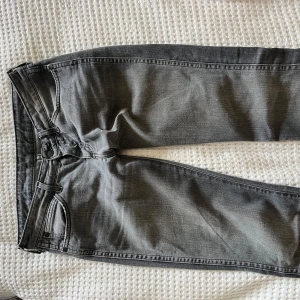 Lågmidjade bootcut jeans  - Midjemått: 38 cm Innerbenslämgd: 80 cm Snygga grå bootcut jeans med klassisk femficksdesign. De har en lågmidjad passform och är perfekta för en avslappnad stil. Jeansen har en dragkedja och knapp framtill.