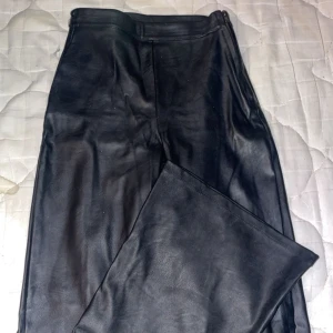 Svarta skinnbyxor från Gina Tricot - Snygga svarta skinnbyxor från Gina Tricot i storlek XXS. Byxorna har en stilren design med hög midja och en tight passform. Perfekta för att ge en edgy touch till din outfit.