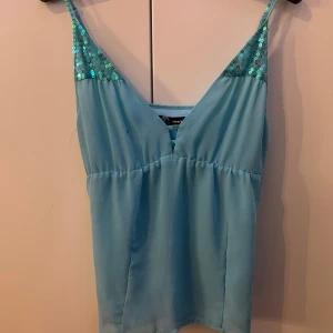 Ljusblå linnetopp från ONLY - Säljer en söt ljusblå linnetopp från ONLY med smala axelband och paljettdetaljer vid bysten. Toppen har en lätt och luftig känsla, perfekt för varma dagar. Passar bra till både jeans och kjol. 💙