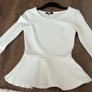 Vit festlig topp/tröja - Säljer en stilren vit topp från H&M med trekvartsärm och peplumdetalj. Perfekt för att ge en elegant touch till din outfit. Toppen har en rund halsringning och är tillverkad i ett strukturerat material.  Kunden står för frakten/ alternativt mötas upp i Norrköping!