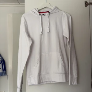 Vit hoodie från Slazenger - Säljer en stilren vit hoodie från Slazenger i storlek M. Den har en klassisk design med långa ärmar och en praktisk magficka. Perfekt för en avslappnad look.