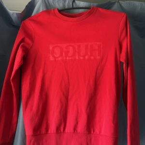 Röd tröja från Hugo Boss - Säljer en snygg röd tröja från Hugo Boss med långärmad design. Tröjan har en subtil logga på framsidan och är tillverkad i ett mjukt material. Perfekt för en stilren look. Priset kan diskuteras 