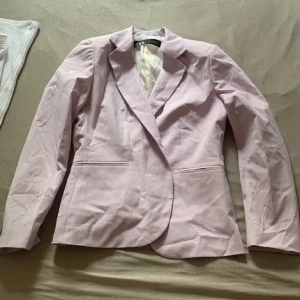 Ljusrosa/lila blazer från Zara🌺 - Snygg ljusrosa kavaj från Zara med klassisk design. Perfekt för att ge en stilren touch till din outfit. Kavajen har en enkel knäppning framtill och är tillverkad i ett mjukt material. Måste strykas då den legat i garderoben annars nyskick❤️