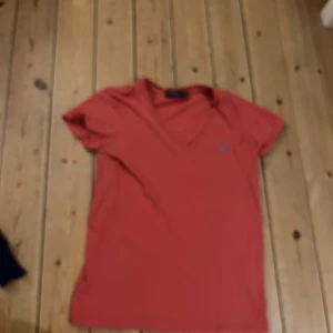 Ralph lauren t shirt - Snygg röd t-shirt med v-ringning och korta ärmar. Perfekt för en avslappnad stil. Den har en liten broderad logga på bröstet.