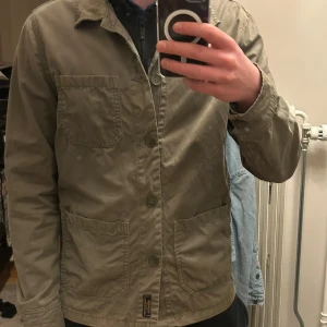 Grön jacka från Morris - Säljer en stilren grön jacka från Morris som är sjukt snygg nu till våren och sommaren🔥🔥. Jackan har en klassisk krage och knäppning framtill. Den är utrustad med flera praktiska fickor och har långa ärmar. Perfekt för en avslappnad look. Skick 8/10 Skriv vid frågor. Passar M/S modellen är 185