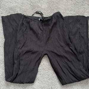 Svarta linnebyxor  - Snygga svarta linnebyxor med en loose passform och praktiska fickor. Byxorna har en bekväm snörning i midjan och är tillverkade i ett lätt och luftigt material. Perfekta för en avslappnad stil.