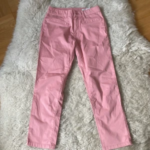 Rosa chinos byxor från Para-mi nya - Snygga rosa chinos byxor från Para-mi  i en klassisk straight fit st.36, nya. De har en hög midja och är tillverkade i bomull, vilket gör dem bekväma och stilrena. Perfekta för en färgglad touch i garderoben!