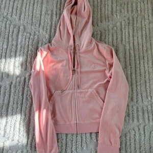 Rosa hoodie från Juicy Couture - Säljer en mjuk och stilren rosa hoodie från Juicy Couture. Den har en dragkedja framtill med ett snyggt JC-emblem och en broderad logga på bröstet. Nästan helt oanvänd.💐