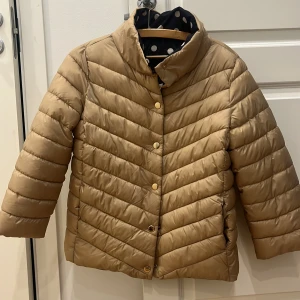 Beige vändbar pufferjacka - Säljer en snygg Herno liknande pufferjacka(beige) som är vändbar med ett prickigt mönster på insidan. Jackan har tre kvarts ärmar och knappar framtill. Perfekt för att hålla sig varm och stilren under kyliga dagar. Endast använd 1 gång alltså nyskick köpt från Springfield i barcelona nypris är 1200kronor 