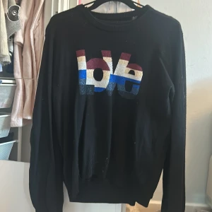 Svart tröja från Zadig & Voltaire  - Snygg svart tröja från Zadig & Voltaire med ett färgglatt 'love'-tryck i rött, beige, blått och grått. Perfekt för att ge din outfit en cool touch. Tröjan har långa ärmar och en bekväm passform. Gammal kollektion så unik ❤️