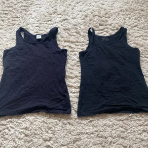 Svarta linnetoppar - Två svarta linnetoppar. Perfekta för lager-på-lager eller att bära som de är. De har en rund halsringning och är ärmlös.