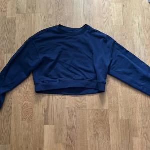 Mörkblå croppad tröja från H&M - Säljer en mörkblå croppad tröja från H&M. Tröjan har långa ärmar och en enkel design som passar perfekt till vardags. Den är gjord i ett mjukt material för extra komfort. Perfekt för en avslappnad stil!