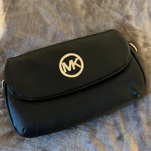 Michael Kors väska - Snygg svart axelväska från Michael kors, finns inget axelband till men kan användas som clutch istället. Många år på nacken därav priset