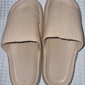 Beige sandaler - Säljer ett par bekväma beige sandaler med ribbad yta och öppen tå. Perfekta för sommarens varma dagar. De har en enkel och stilren design med en bred rem över foten. Från Fotprofsen.