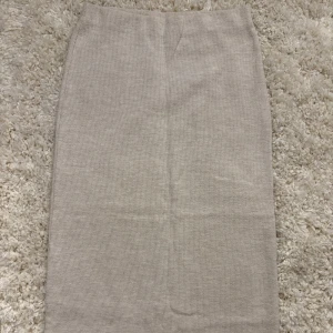 Beige långkjol - Säljer en beige  långkjol med rak passform. Kjolen är enkel och stilren, perfekt att matcha med olika toppar. Materialet är tjockare, mjukt och stretchigt för en bekväm känsla. Sparsamt använd!