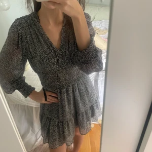 Svart och vit mönstrad klänning - Snygg svart och vit mönstrad klänning med v-ringning och volangdetaljer. Perfekt för både vardag och fest! ❤️‍🔥❤️‍🔥Endast använd en gång