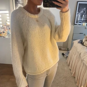 Vit stickad tröja med rund hals - Mysig vit stickad tröja med rund hals och långa ärmar. Tröjan har en avslappnad passform och är perfekt för kyligare dagar. Enkel och stilren design som passar till det mesta.