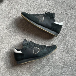 Philippe model trpx - Svarta Philippe models i storlek 43. Skorna är i okej skick eftersom dem har lite fläckar, en fläck på höger tå av skon men sen är det mest fläckar på skosnörena (vilket kan gå att byta/tvätta). Sedan är dem synligt använda på mockan vid hälen. Utöver detta är skorna i fint skick, inga hål. !Box medföljer ej! Skicka gärna om du har frågor eller prisförslag!