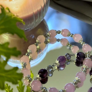 Armband med rosa och lila pärlor - Säljer ett fint armband med rosa och lila pärlor, dekorerat med små glittriga detaljer mellan pärlorna. Perfekt accessoar för att ge din outfit en färgklick och lite extra glans.