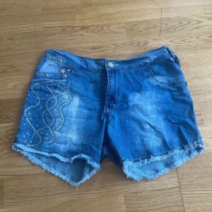 Blå Denim short y 2k M-L-XL - Snygga blå jeansshorts med fransig kant och dekorativa nitar på både fram- och bakficka. Shortsen har normal passform 