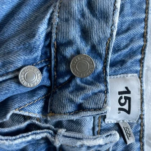 Blå jeans från 157 - Säljer ett par klassiska blå jeans från 157. De har en rak passform och är tillverkade i denim med knappdetaljer. Perfekta för en avslappnad stil.