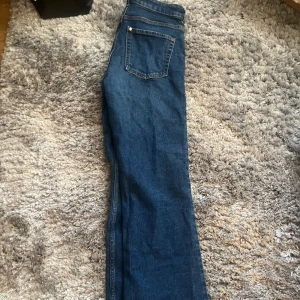 Blå bootcut jeans - Snygga blå bootcut jeans med hög midja. Klassisk femficksdesign och dragkedja med knapp framtill. Perfekta för en avslappnad stil.