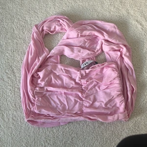 Rosa tubtopp från Zara - Säljer en söt rosa tubtopp från Zara. Toppen har en rynkad design och är perfekt för varma dagar. Den är tillverkad i ett mjukt och bekvämt material. Perfekt för att styla med jeans eller kjol!