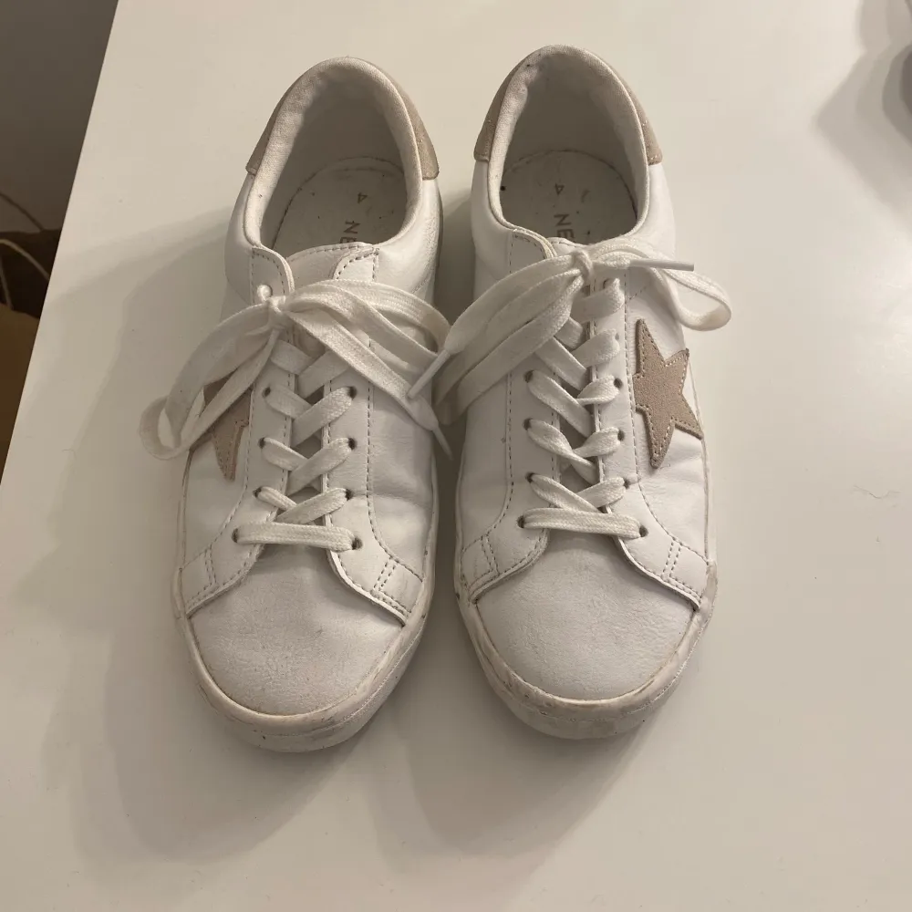 Säljer vita sneakers från Next med en beige stjärna på sidan. Lite smått smutsiga vid nedre delen av skon men annars är den väldigt vita på resten av skon.. Kengät.