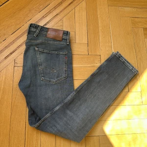 Replay anbass - Snygga blå jeans från Replay med klassisk femficksdesign och en läderpatch baktill. Jeansen har en slim passform och är perfekta för en stilren look. De är tillverkade i ett slitstarkt denimtyg. Finns en liten fläck (bild 4) men syns inte vid användning. W31 L32. Pris kan diskuteras vid snabb affär!