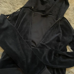 Mörkblå velour hoodie från Juicy Couture - Säljer en mörkblå hoodie i mjuk velour från Juicy Couture. Jackan har huva, dragkedja med guldfärgad JC-detalj (som har blivit under tiden då jag använt denna mycket) och långa ärmar. 
