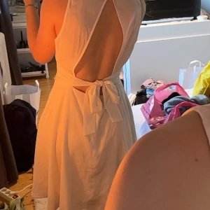 Vit ärmlös klänning med öppen rygg - Säljer en stilren vit klänning med öppen rygg och knytning i midjan. Klänningen är ärmlös och har en elegant. Den är gjord i ett lätt och bekvämt material. Passar så bra till skolavslutning eller student! Köptes på Sellpy och hade då ett hål i en söm men som jag sydde fast igen(fråga för bild på det) annars super fint skick. Fråga vid fler funderingar💕