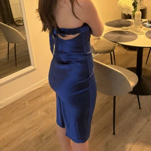 Blå axelbandslös klänning - Snygg blå axelbandslös klänning i satin med en elegant passform. 