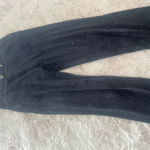 Marinblåa byxor från Juicy Couture - Marinblåa mjukisbyxor från Juicy Couture i velour med broderad logga framtill och fickor med knappar bak. Köpta i kids brandstore för 899kr. Det finns snören i båda hål men fick inte upp ena. Metall saken på snöret har gått av på ena delen men sitter kvar på andra. 