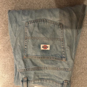 Ljusblå jeansbyxor från Dickies - Säljer ett par klassiska ljusblå jeansbyxor från Dickies med fem fickor och Dickies-logga på bakfickan. Byxorna har normal passform och raka ben, perfekta för en avslappnad stil.