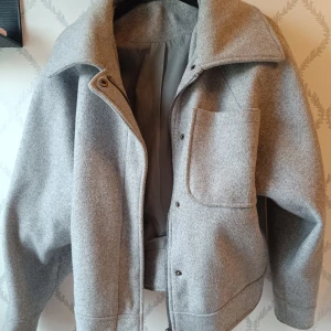 Grå vårjacka  - Snygg grå jacka med stor krage och dragkedja framtill. Jackan har en stor bröstficka och breda muddar nedtill. En perfekt vårjacka!!! Storlek XS men är stor i storlek skulle jag säga så passar S ockås. Lite nopprig på vissa ställen, där av priset. Skirv för fler bilder 💖🤗.