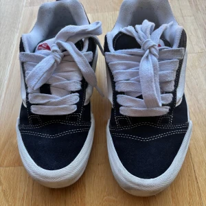 Svarta och vita sneakers från Vans - Säljer ett par klassiska Vans sneakers i blått och vitt med vit sula och breda vita skosnören. Skorna har den ikoniska sidoremsan och tydliga kontrastsömmar. 