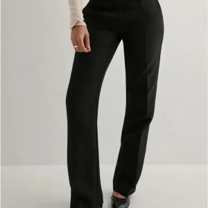 Svarta kostymbyxor lågmidjade - Snygga svarta kostymbyxor med låg midja och rak passform. Perfekta för en stilren look. Byxorna har en klassisk design som passar till många olika tillfällen. Finns tecken på användning med knoppror därav priset.