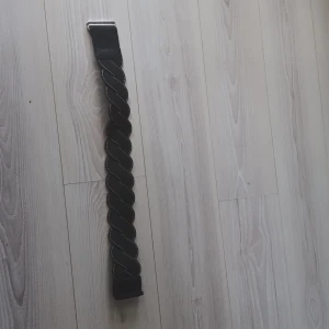 Svart flätat bälte - Snyggt svart bälte med flätad design och silverfärgat spänne. Perfekt för att ge en stilren touch till din outfit. Passar både till jeans och klänning.