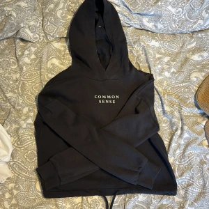 Svart hoodie från Gina Tricot - Säljer en svart hoodie från Gina Tricot. Den har en justerbar dragsko i nederkanten och ribbade muddar vid ärmsluten. Storlek xs