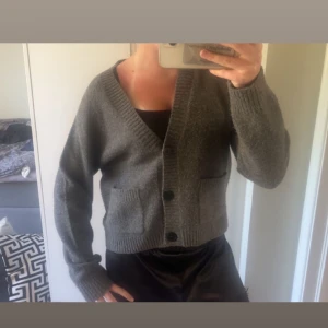 Grå stickad kofta med knappar - Mysig grå stickad kofta med två stora fickor framtill och djup v-ringning. Koftan har långa ärmar, ribbade muddar och helt perfekt till sena sommarkvällar.☺️💗