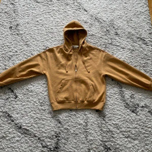 Beige hoodie från H&M - Säljer en beige hoodie från H&M i storlek XS. Tröjan har dragkedja framtill. Perfekt för en avslappnad stil och enkel att matcha med det mesta.